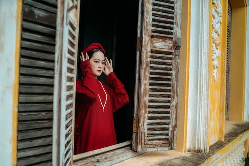 有关传统服装, 传统的房子, 在窗户旁边的免费素材图片