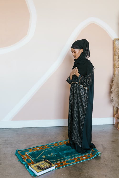 黑色头巾的女人站在蓝色和棕色区域地毯 · 免费素材图片