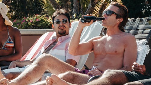 戴着黑色太阳镜坐在白色和红色的条纹椅子上的裸照人 · 免费素材图片