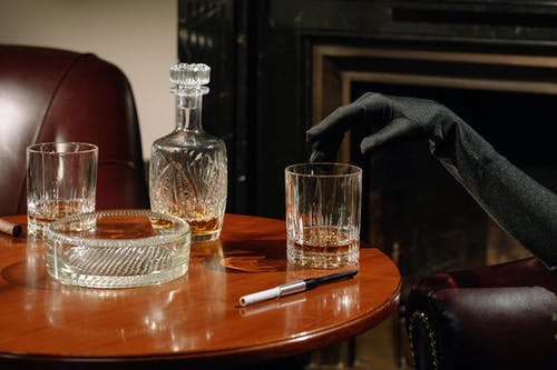 有关威士忌, 手, 木桌的免费素材图片