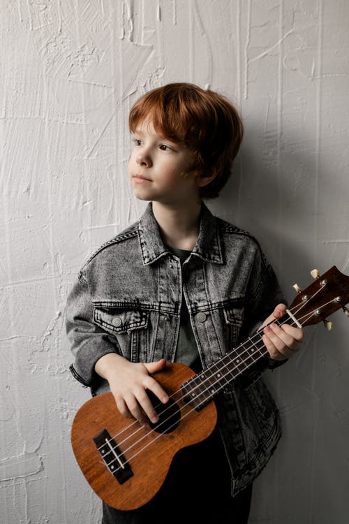 蓝色牛仔夹克打棕色原声吉他的男孩 · 免费素材图片