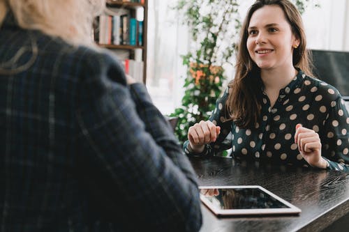 坐在木桌旁微笑的女人 · 免费素材图片