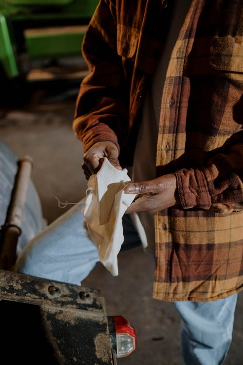 拿着白色纺织品的棕色外套的人 · 免费素材图片