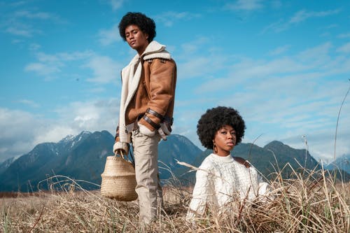 一个男人站在一个坐在草地上的女人旁边 · 免费素材图片