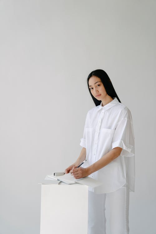 站在白墙前的白色礼服衬衫的女人 · 免费素材图片