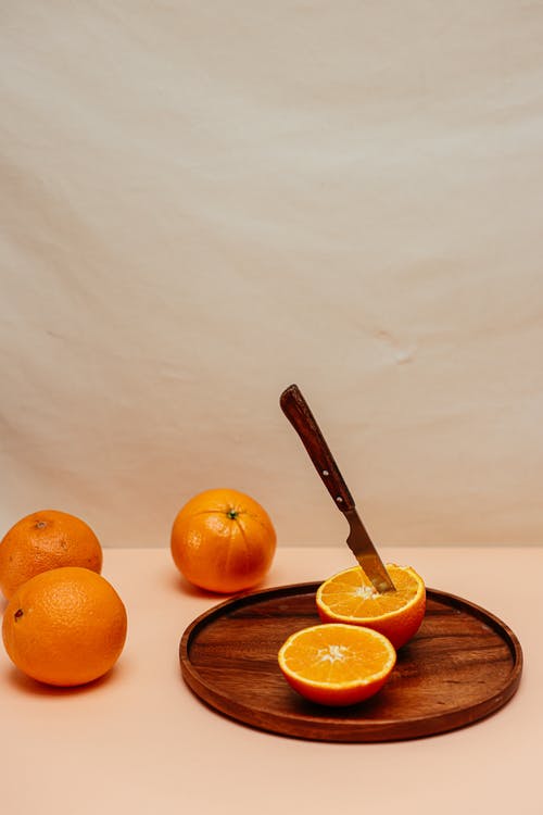 棕色木制圆板上的橙色水果 · 免费素材图片