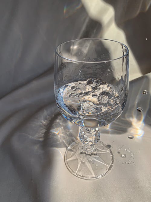 白色纺织品上的透明酒杯 · 免费素材图片