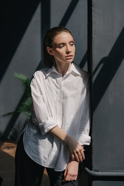 站在黑墙附近的白色礼服衬衫的女人 · 免费素材图片