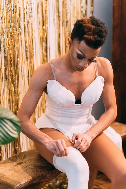 白色意大利面条皮带顶部坐在棕色木椅上的女人 · 免费素材图片