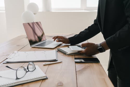 黑色长袖衬衫，棕色的木桌上使用macbook Pro的人 · 免费素材图片