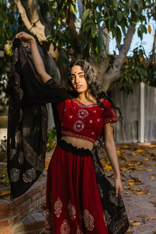 红色和黑色的花裙子，站在棕色的叶子上的女人 · 免费素材图片