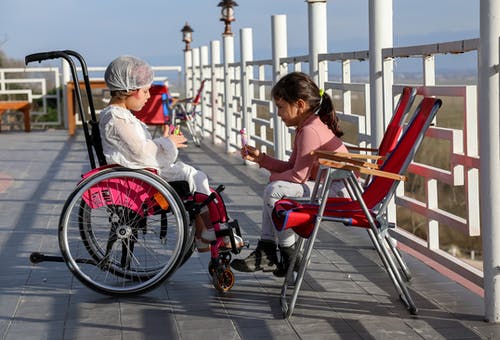 坐在红色和白色轮椅上的棕色衬衫的女人 · 免费素材图片