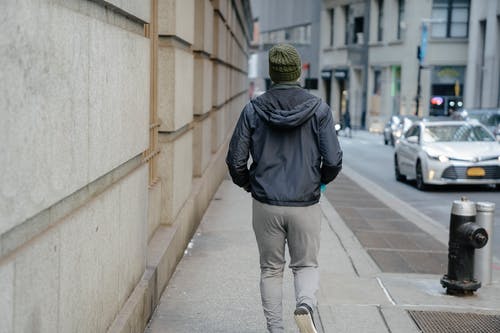 黑色连帽衫和灰色裤子在人行道上行走的人 · 免费素材图片