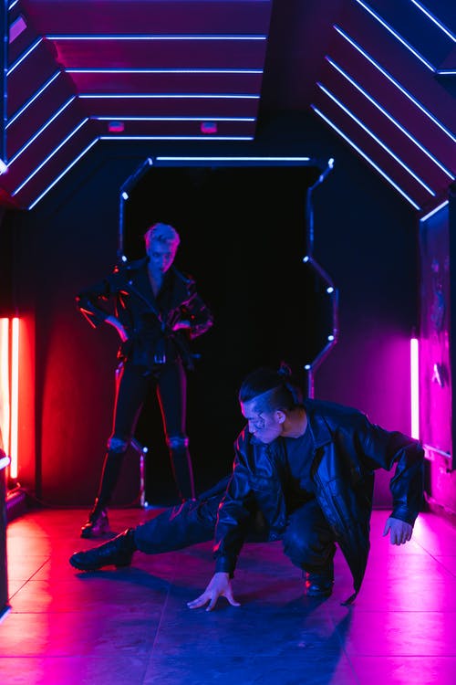 身穿黑色夹克和裤子的男人，身后站着一个女人 · 免费素材图片