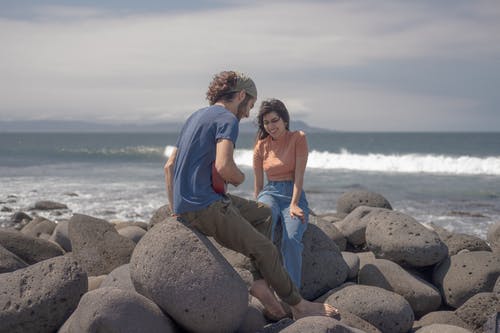 有关一对, 坐, 岩石海岸的免费素材图片