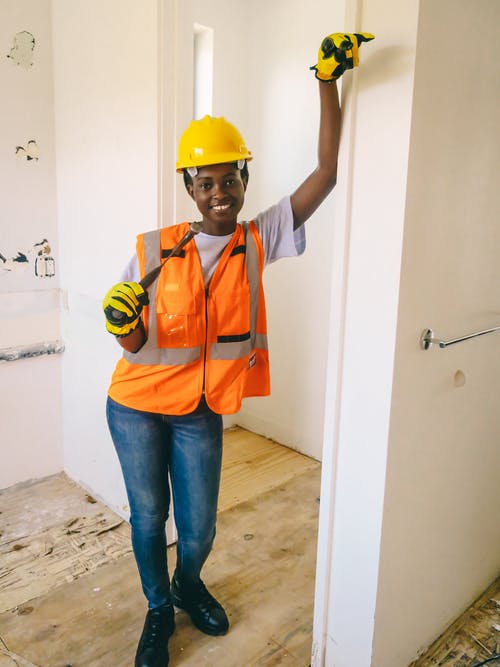 男孩在橙色背心和蓝色牛仔牛仔裤戴着黄色安全帽 · 免费素材图片