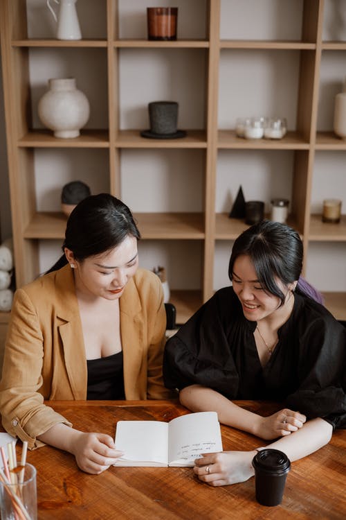 穿着棕色西装外套的女人坐在穿着黑色长袖衬衫的女人旁边 · 免费素材图片