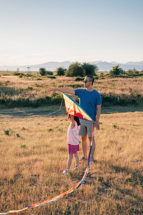 爸爸和女儿在草地上玩风筝 · 免费素材图片