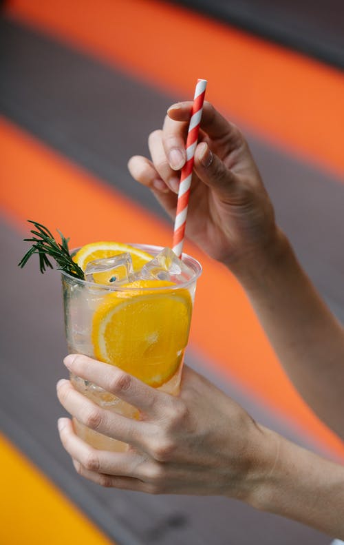 持有与黄色液体的透明水杯的人 · 免费素材图片