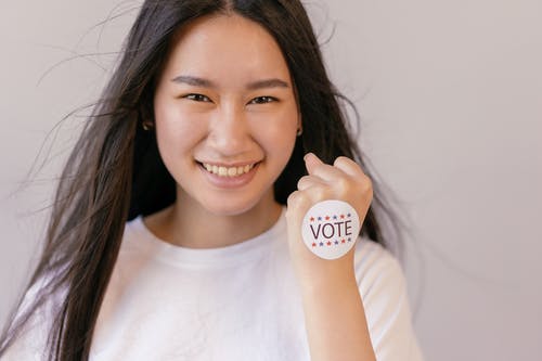 微笑的女人，她的拳头上贴着投票贴纸 · 免费素材图片