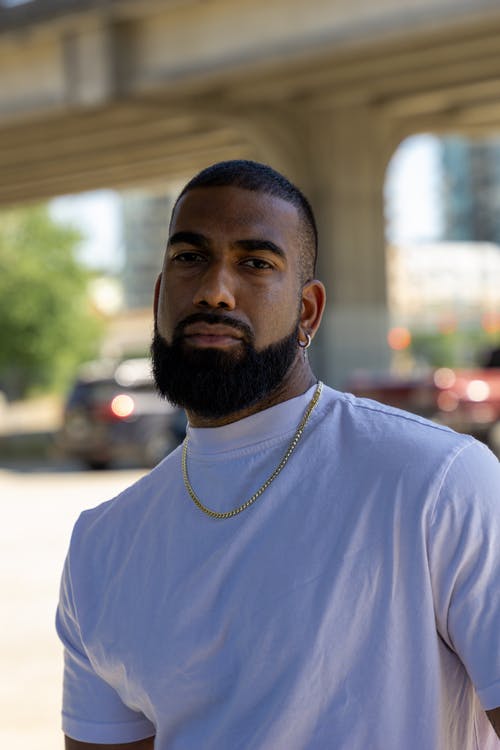 白衬衫和金项链的大胡子男子看着相机的浅焦点照片 · 免费素材图片