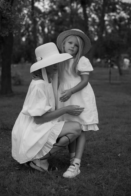 蹲在草地上的白色连衣裙和帽子的女人 · 免费素材图片