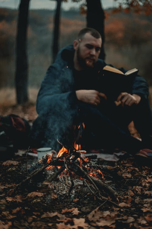 一个人坐在篝火旁看书 · 免费素材图片
