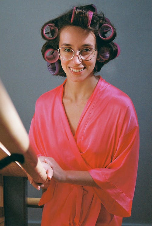 一个穿着浴袍的女人卷着她的头发 · 免费素材图片