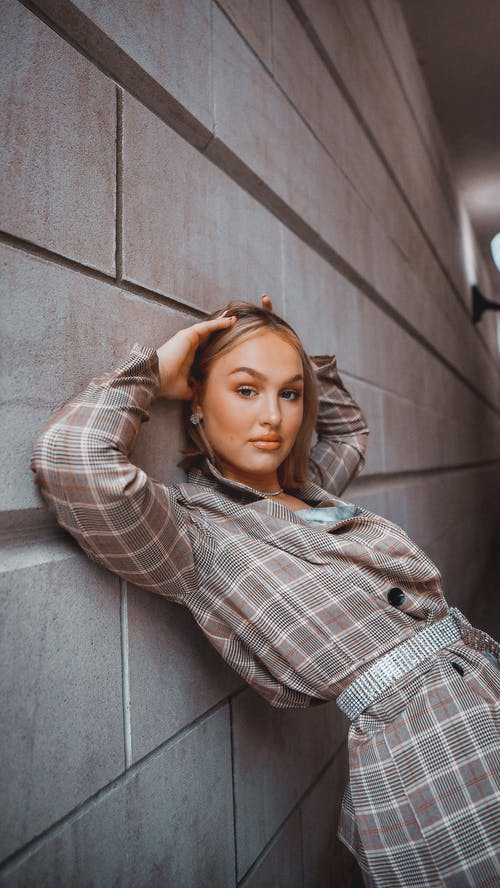 一个美丽的女人靠在墙上摆姿势 · 免费素材图片