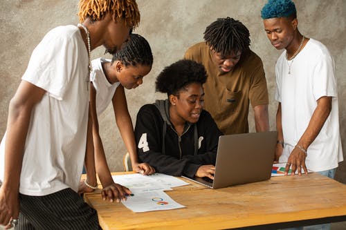 被男人包围的女人看着笔记本电脑 · 免费素材图片