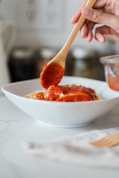 一个人在意大利面里放番茄酱 · 免费素材图片