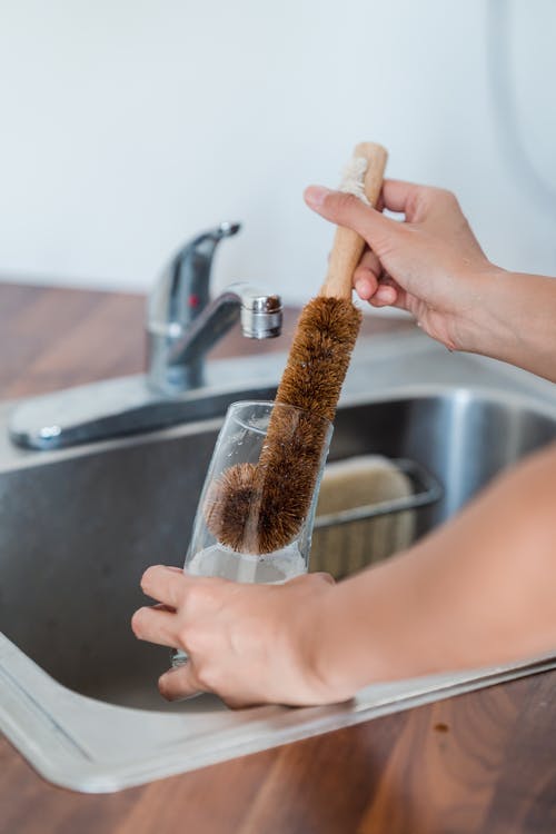 用刷子清洁玻璃的人的特写照片 · 免费素材图片