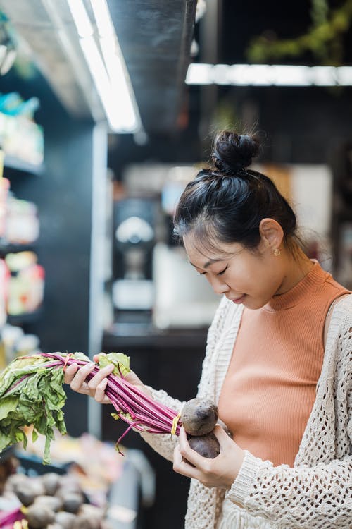 一个女人在超市里拿着甜菜根 · 免费素材图片