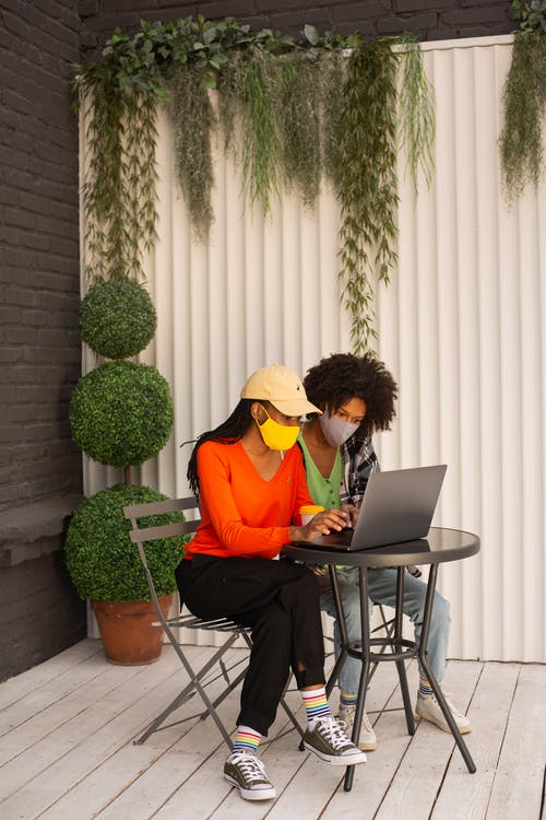 戴口罩使用笔记本电脑的女性 · 免费素材图片