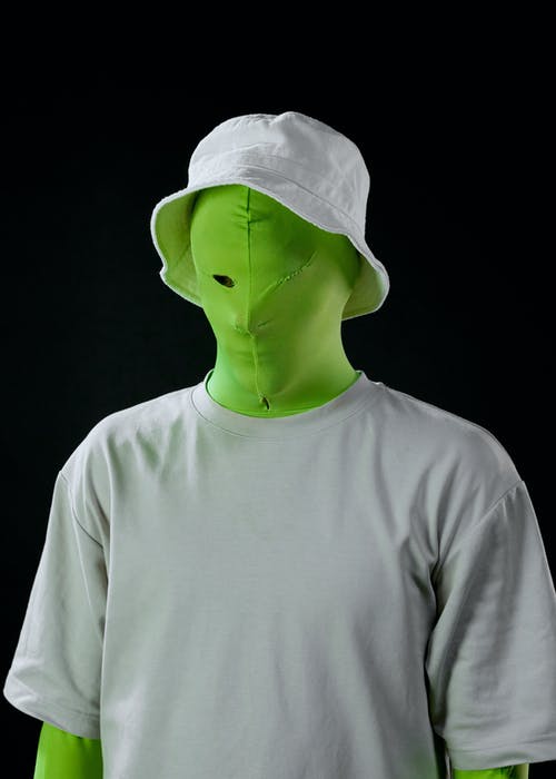 一个穿着灰色衬衫和白色帽子的绿屏西装的人 · 免费素材图片