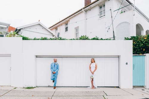 穿着蓝色外套的男人站在一个穿着婚纱的女人附近 · 免费素材图片