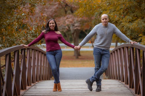 男人和女人在木桥上牵手的牛仔牛仔裤 · 免费素材图片