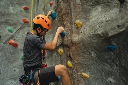 男性登山者在训练过程中在人工墙上上升 · 免费素材图片