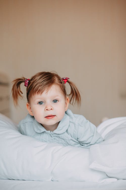 女婴在床上穿绿色衣领的毛衣 · 免费素材图片