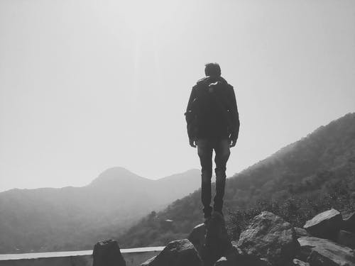 人站在悬崖上的灰度照片 · 免费素材图片