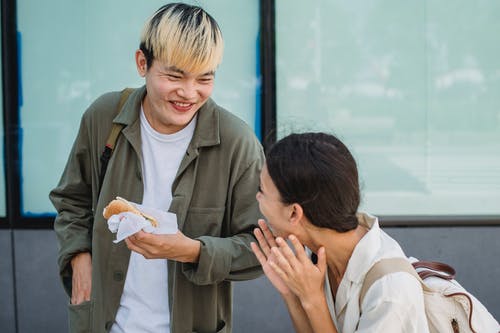 快乐的亚洲夫妻在大街上享受热狗 · 免费素材图片