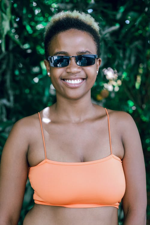 橙色意大利面条表带顶部戴着黑色太阳镜的女人 · 免费素材图片