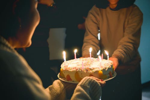 两人拿着点燃的蜡烛蛋糕 · 免费素材图片