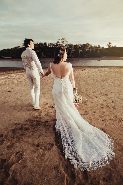 新郎和新娘站在水体附近 · 免费素材图片