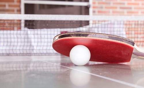 红色乒乓球拍下的白色乒乓球 · 免费素材图片