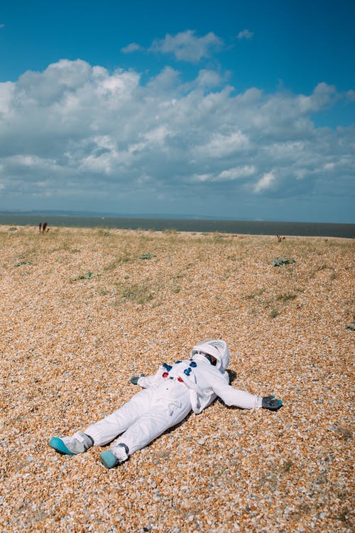 躺在地上的宇航员服装的人 · 免费素材图片