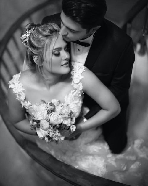 女人穿着婚纱捧着花束的灰度照片 · 免费素材图片