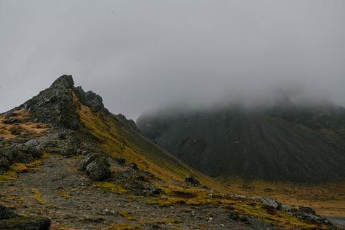 白色天空下的绿色和棕色山 · 免费素材图片