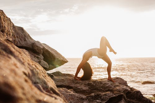 女人在岩石上做瑜伽 · 免费素材图片