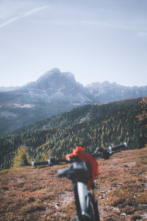 坐在黑岩看着山上的红色外套的人 · 免费素材图片
